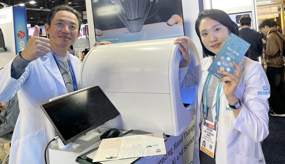 CES 2026 전시장 메리핸드 부스에서 박은수 대표(오른쪽)와 관계자가 AI 손 재활 진단 장비를 소개하며 포즈를 취하고 있다. | 촬영 – 에이빙뉴스