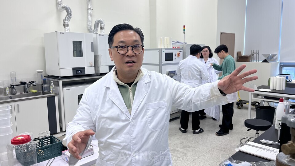 에코리뉴 최덕현 대표가 연구소에서 나노표면코팅 필터의 작동 원리와 유수분리·정제 기술 전략을 설명하고 있다. 뒤편에서는 연구진이 리누바 필터의 코팅·여과 성능 시험을 진행하고 있다. | 촬영 - 에이빙뉴스